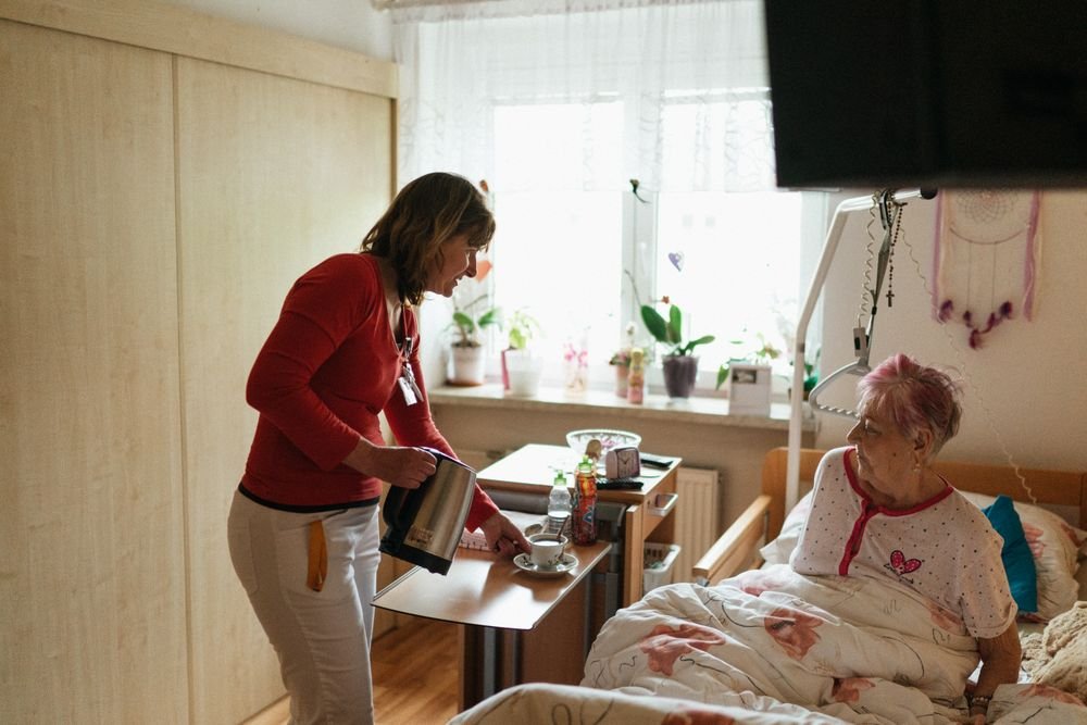 A caregiver serving tea to a resident in a cozy room