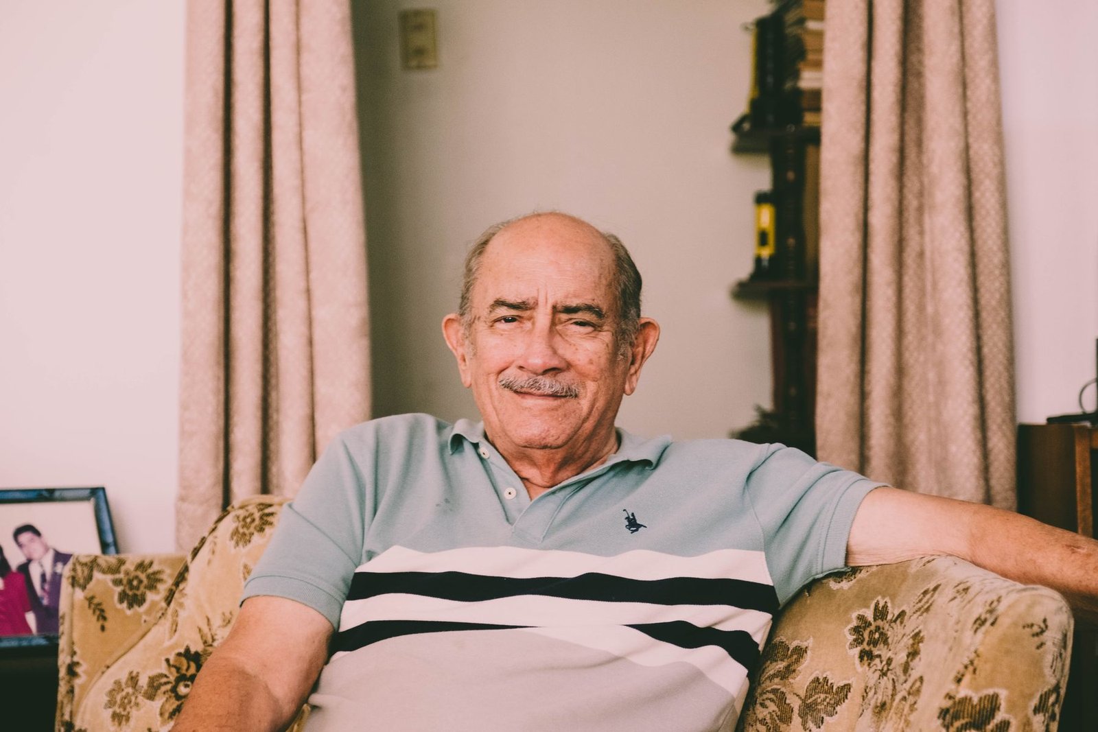 A cheerful older man relaxing on a sofa in a warmly decorated living room