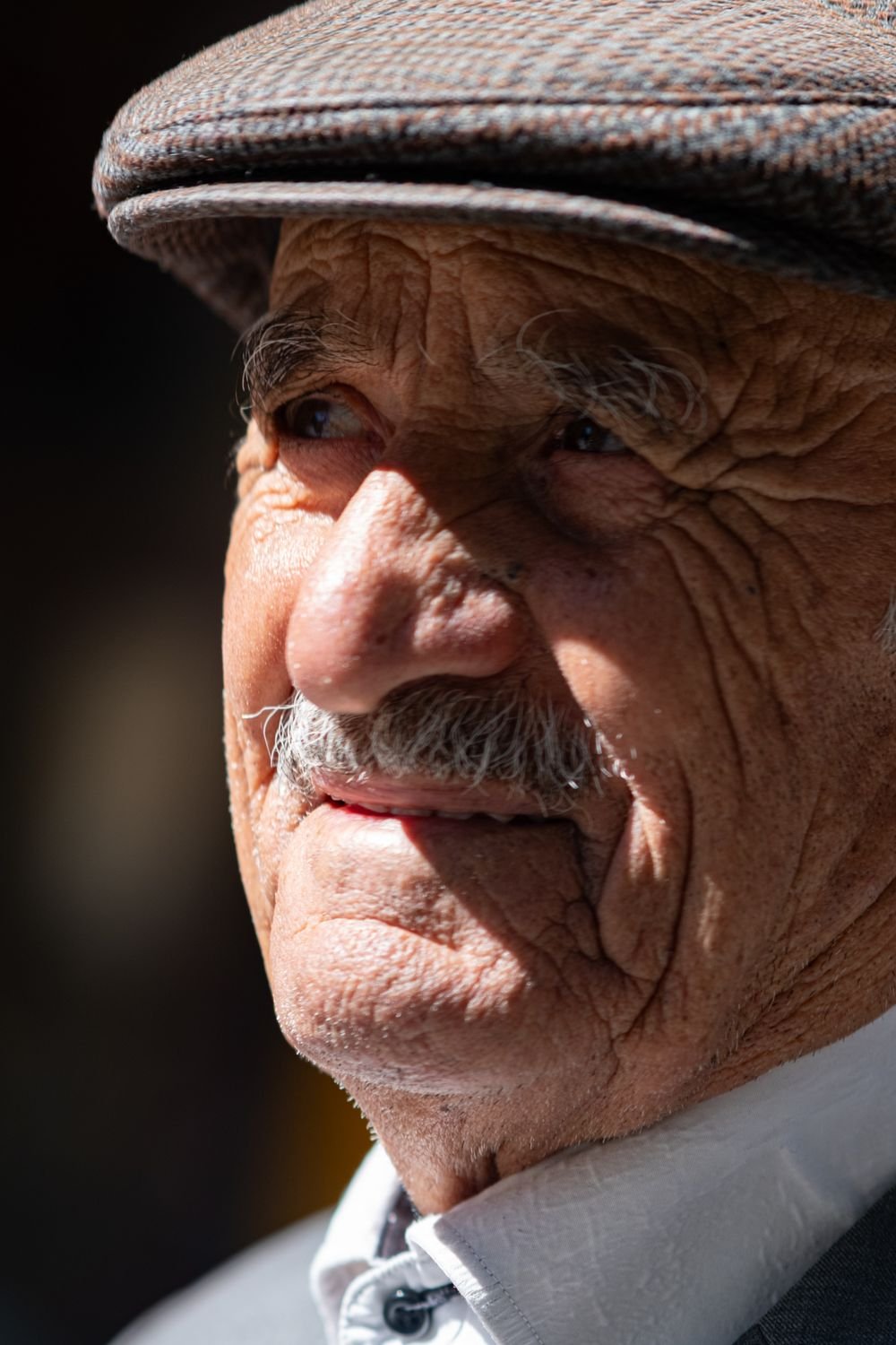 Portrait of a smiling older man wearing a cap in natural sunlight
