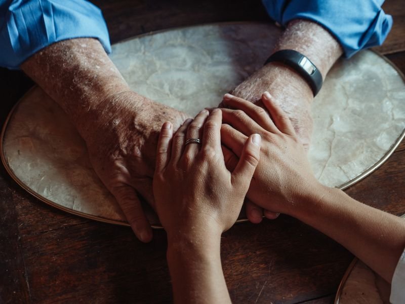 An older hand held gently in a younger hand